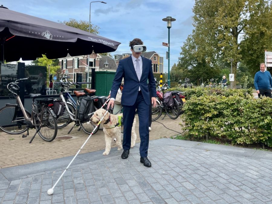 Burgemeester van Barneveld met VR-bril en blindegeleidestok (ook wel taststok of witte stok genoemd)